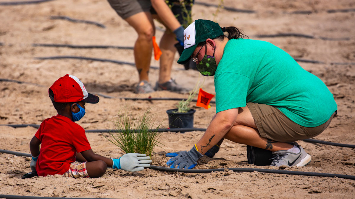 A mother and young child plant a shrub at the Las Vegas Wash