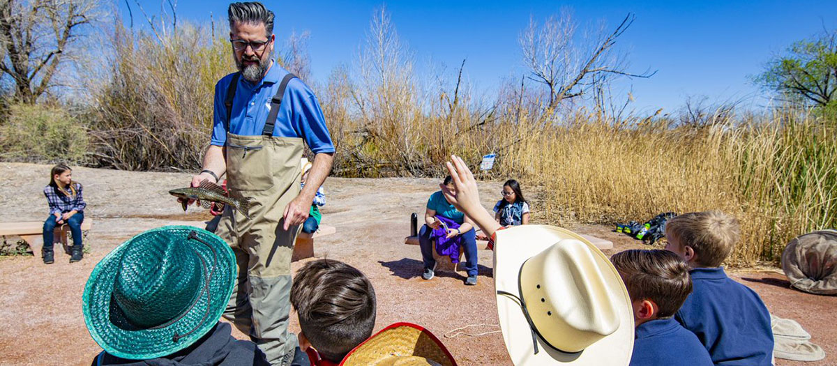 Staff member showing fish to school children